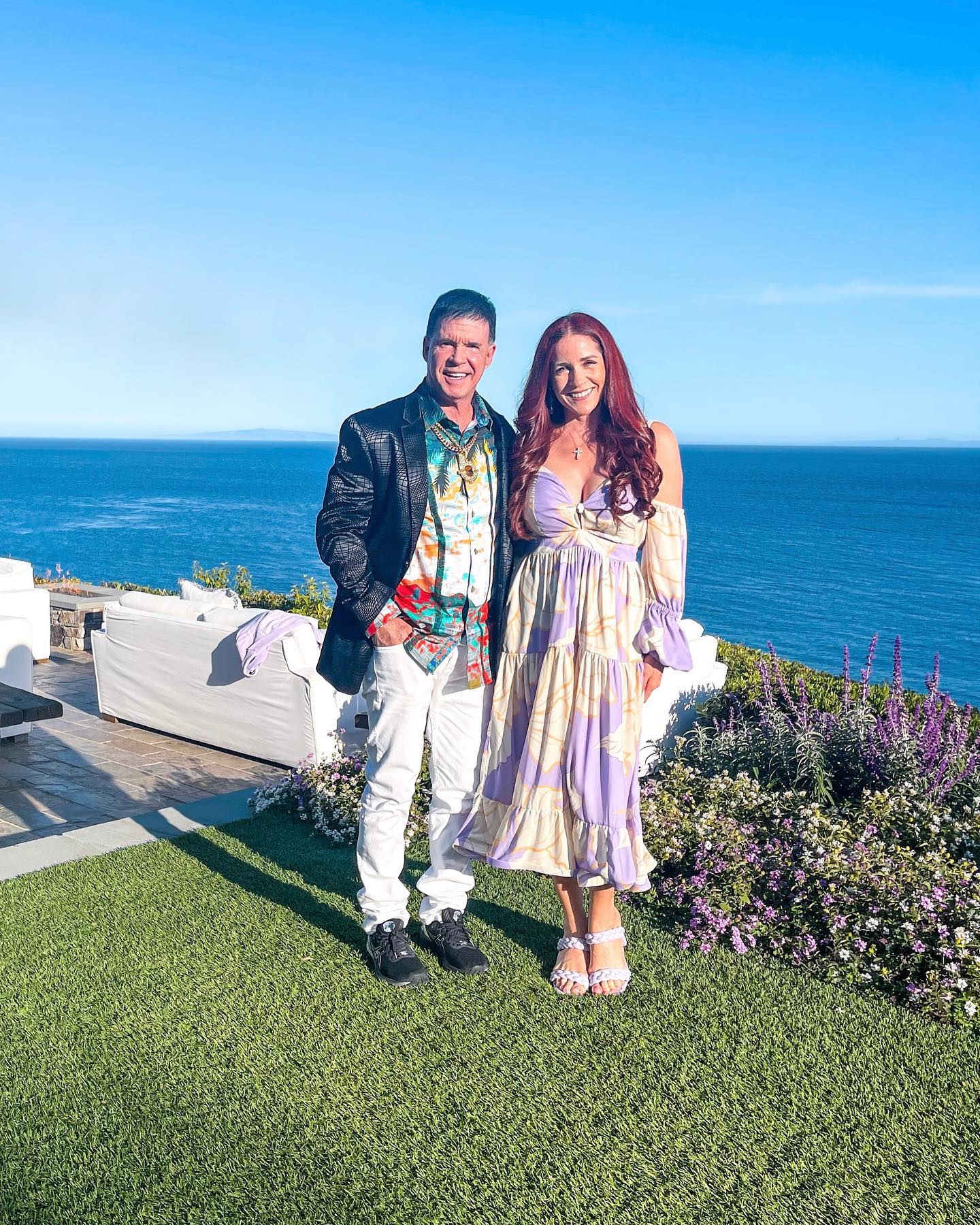 Jack Owoc and his wife, Meg Liz Owoc, standing in front of the ocean by a house