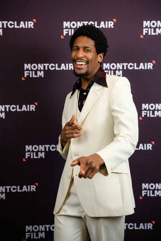 Jon Batiste, wearing a cream outfit at an event