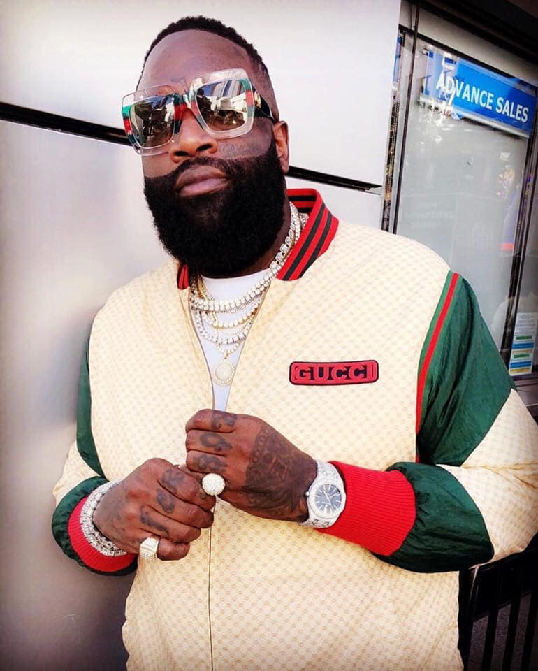 Rick Ross, wearing big sunglasses and multicolor jacket