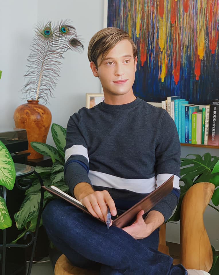 Tyler Henry sitting in a chair, holding a notebook and pen