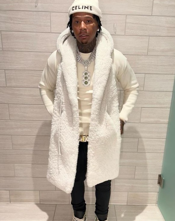 Moneybagg Yo in a white coat against a white wall