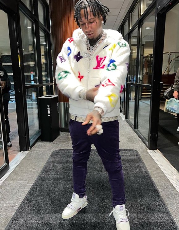 Moneybagg Yo in a hallway, wearing a patterned jacket