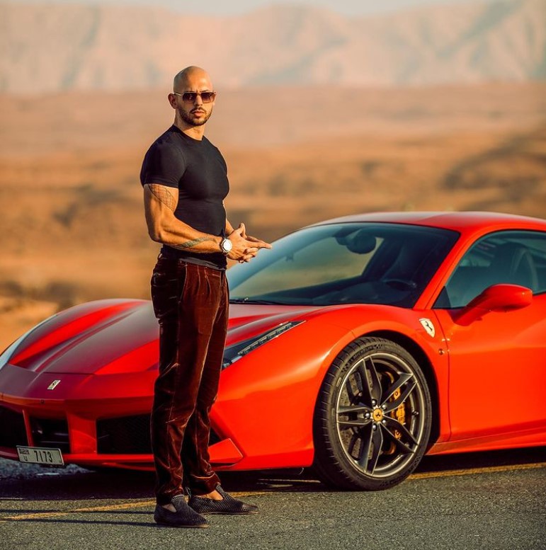 Andrew Tate in Oman, standing next to an orange vehicle