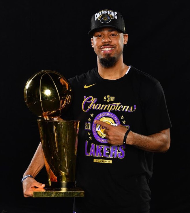 Quinn Cook, wearing a black NBA Champion tee and holding a trophy