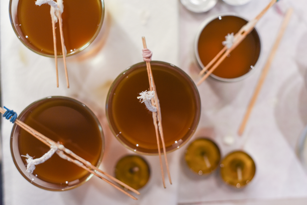 candle making process pouring of liquid wax into jars close up