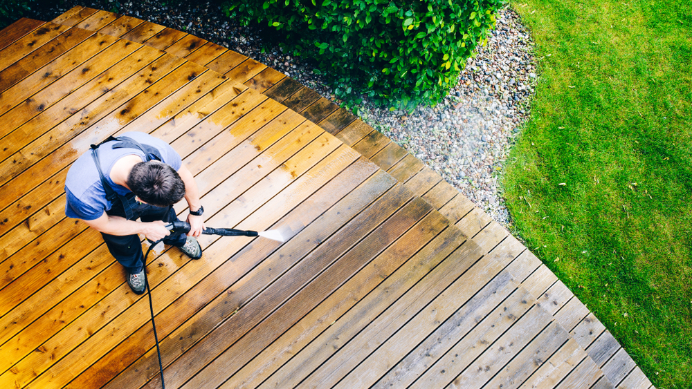 man cleaning terrace during day time with pressure washer