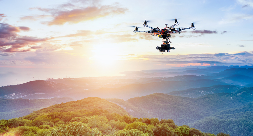 drone copter flying with digital camera on mountains during sunset