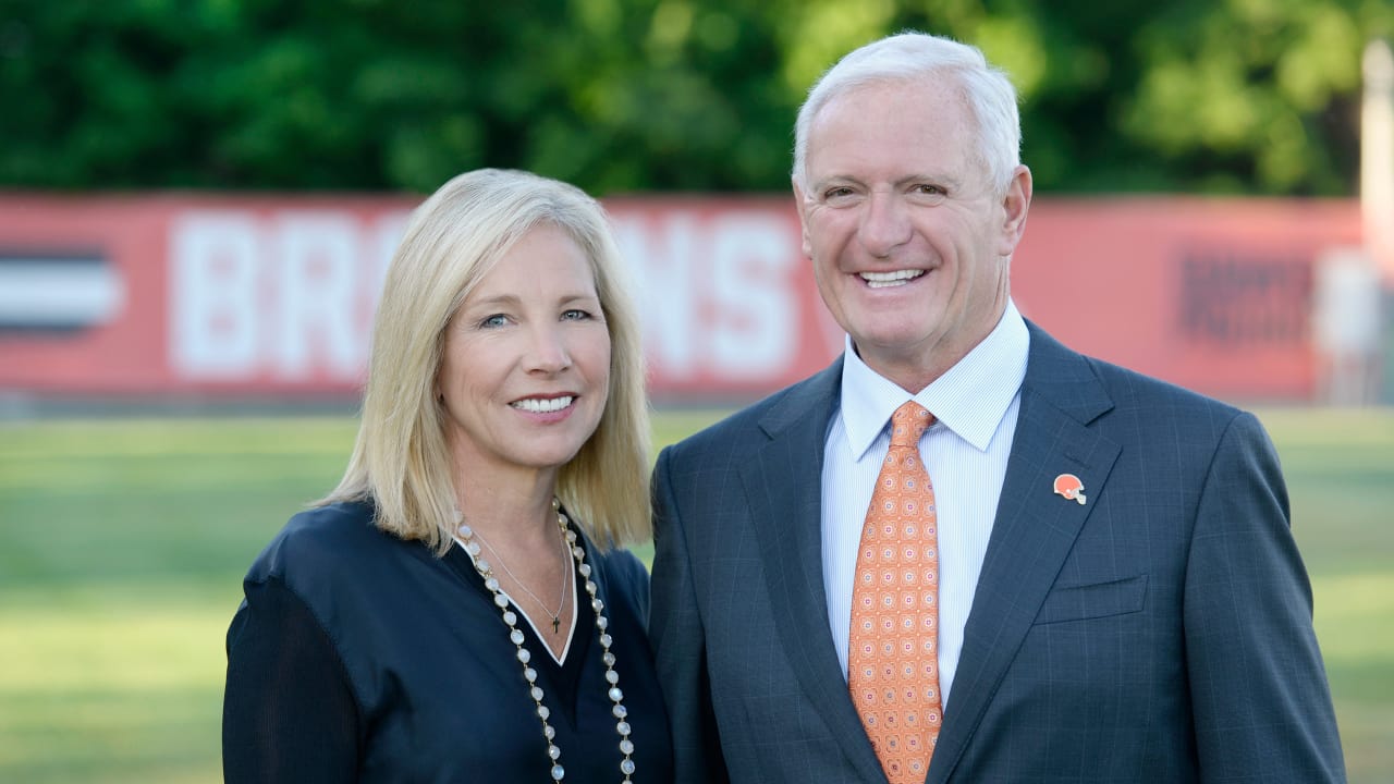Dee and Jimmy Haslam on a field with Cleveland Browns banner behind them