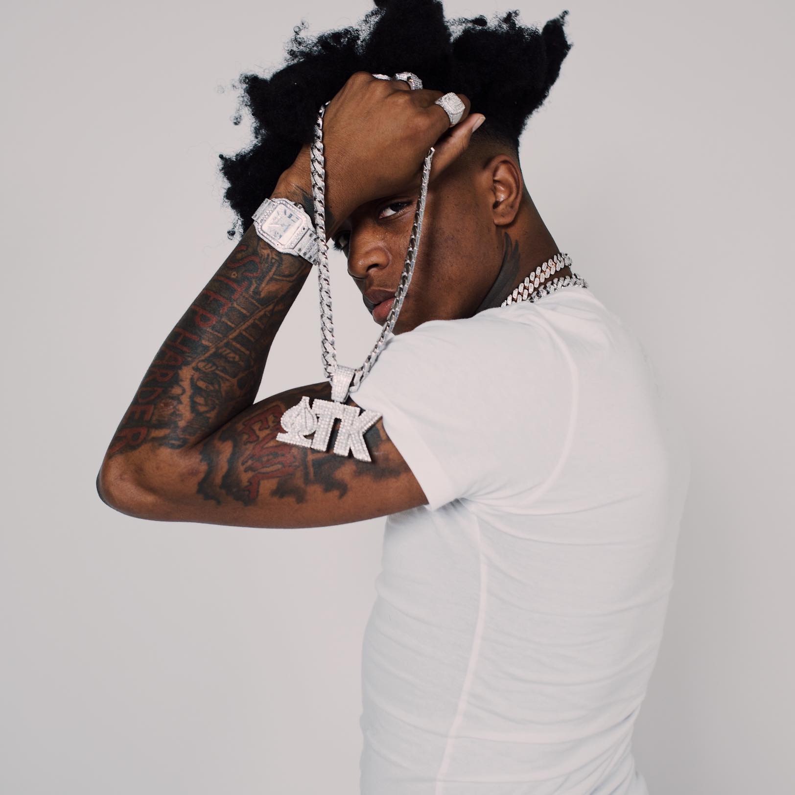 Yungeen Ace in white, holding a silver chain in front of a light background