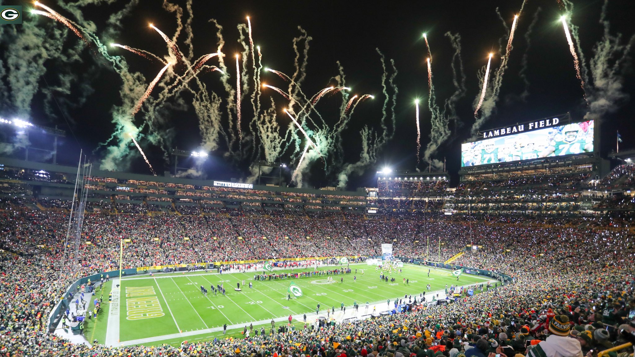 A packed out Lambeau Field with fireworks shooting off in the background.